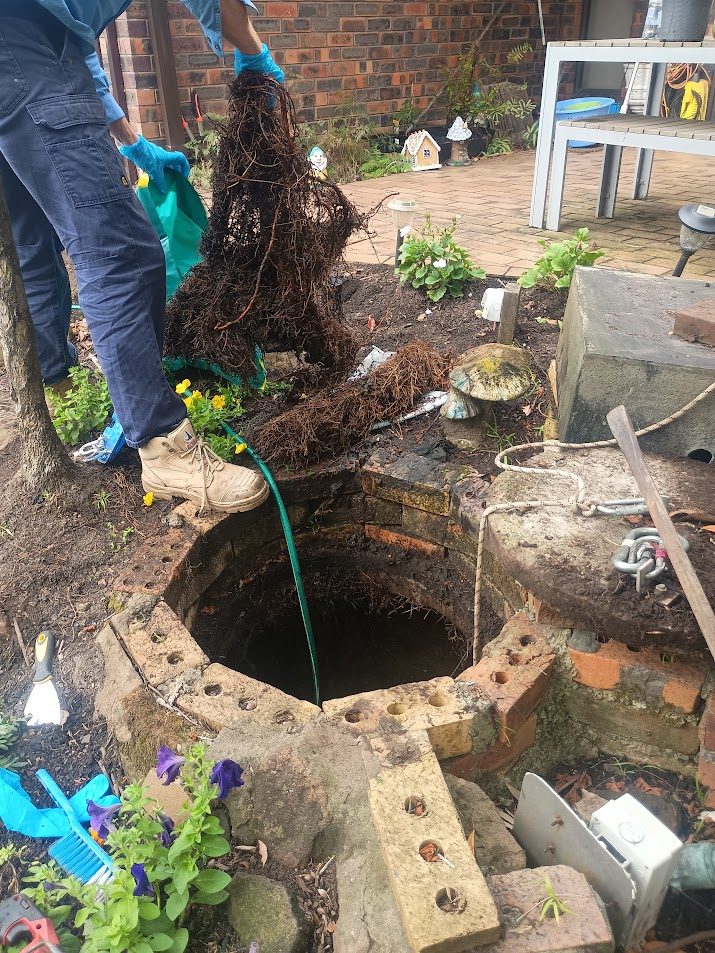 Ayden lifting massive root mass from a brick pump pit during service in Yowie Bay