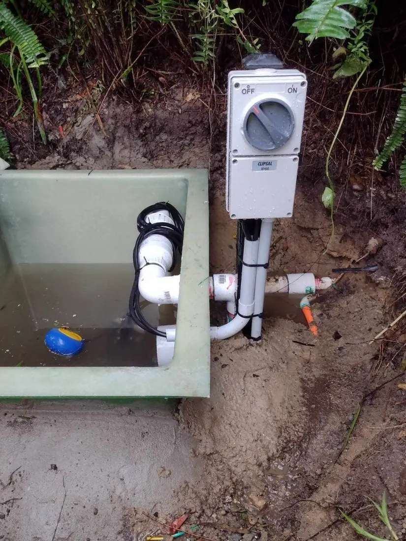 Completed sewer pump pit installation on a Sydney home — fibreglass pit with neat pipework and a Clipsal IP66 electrical isolator wired in