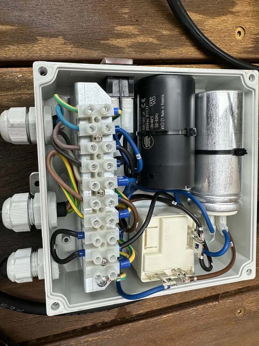 The external capacitor box of a DAB sewer pump opened up, showing the capacitors and terminal wiring mounted separately from the pump