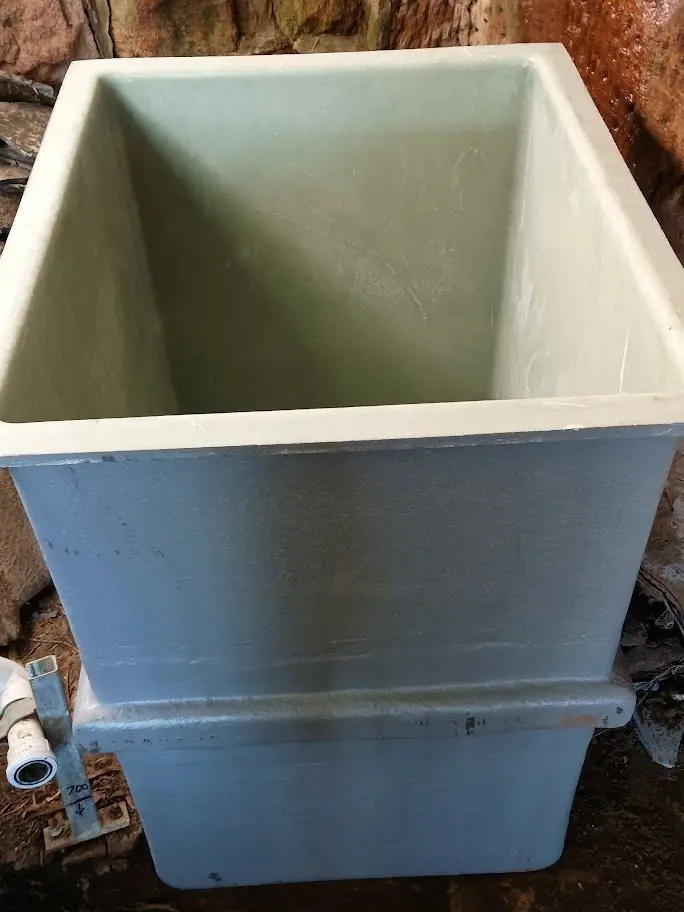 Empty custom fibreglass pump pit ready for installation, showing the moulded chamber and external ribbing