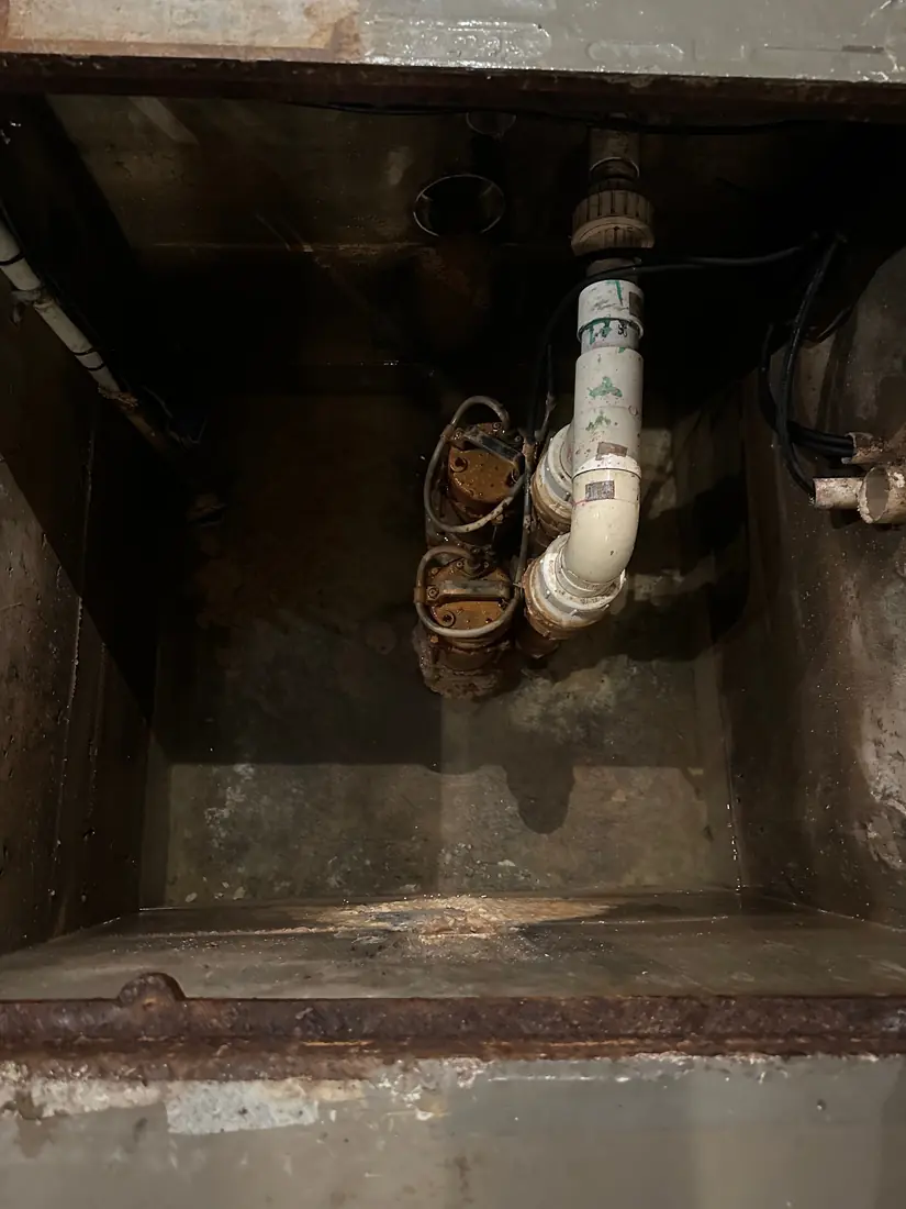 Two faulty Ultraflow pumps and old pipework crammed in the corner of a Chiswick pit before replacement