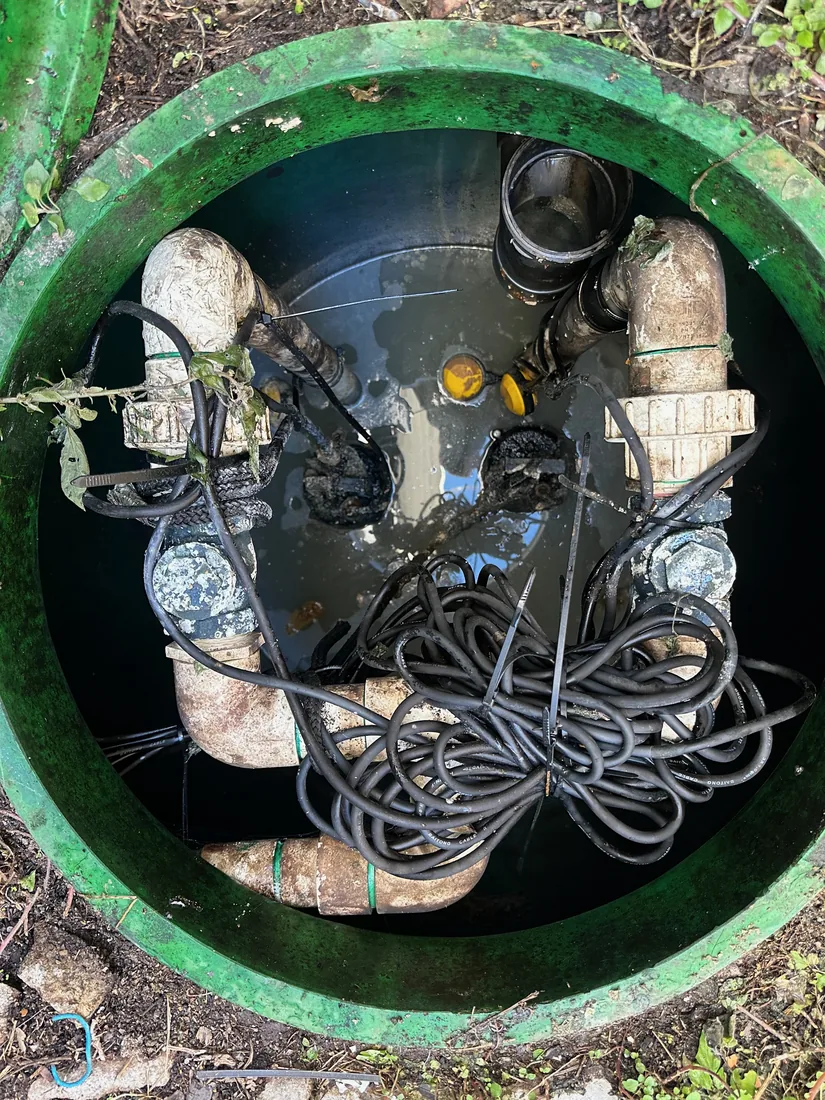 Two undersized 0.75kW cutter pumps in a Yowie Bay pit on a pressurised main, with tangled cabling and a dual-pump controller before replacement