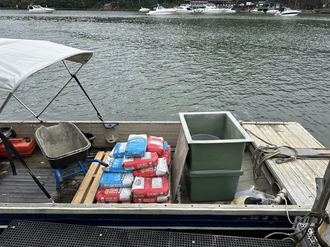 New fibreglass pump pit, bags of concrete and a wheelbarrow loaded on a barge for delivery to a waterfront Sydney property