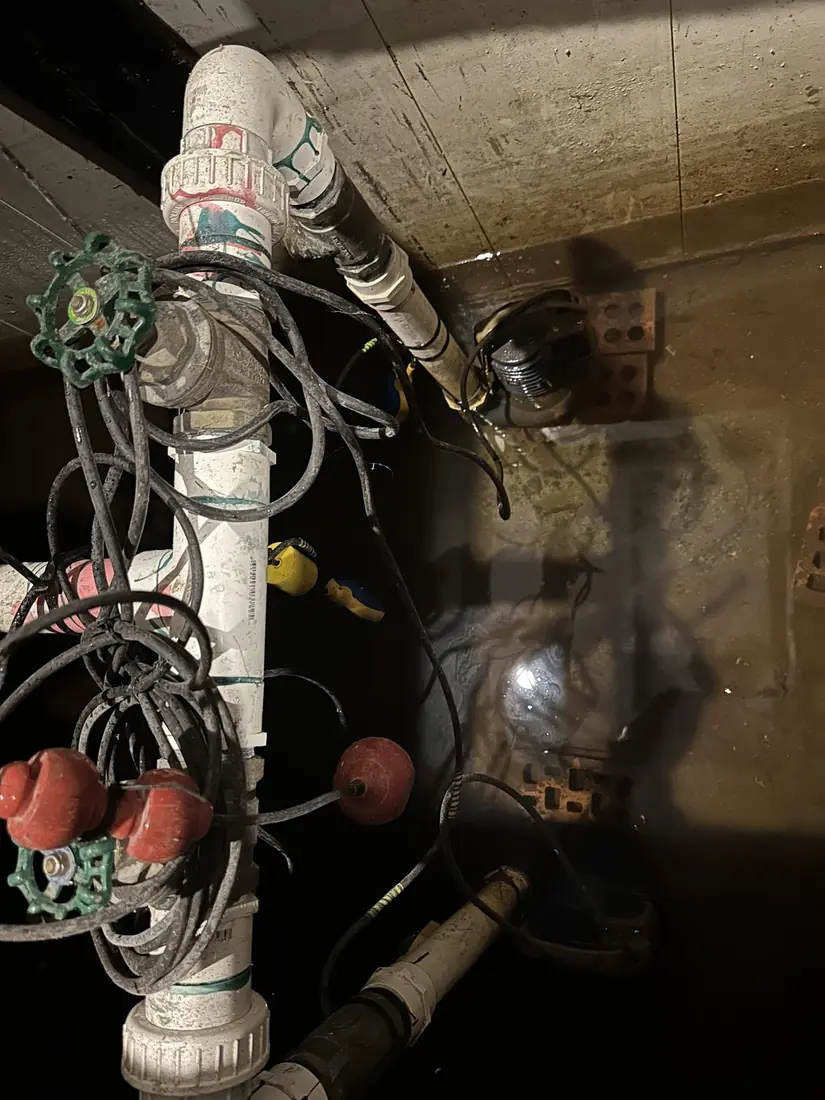 A dual pump pit under a Cronulla apartment garage as found, with loose cabling fouling the float switches