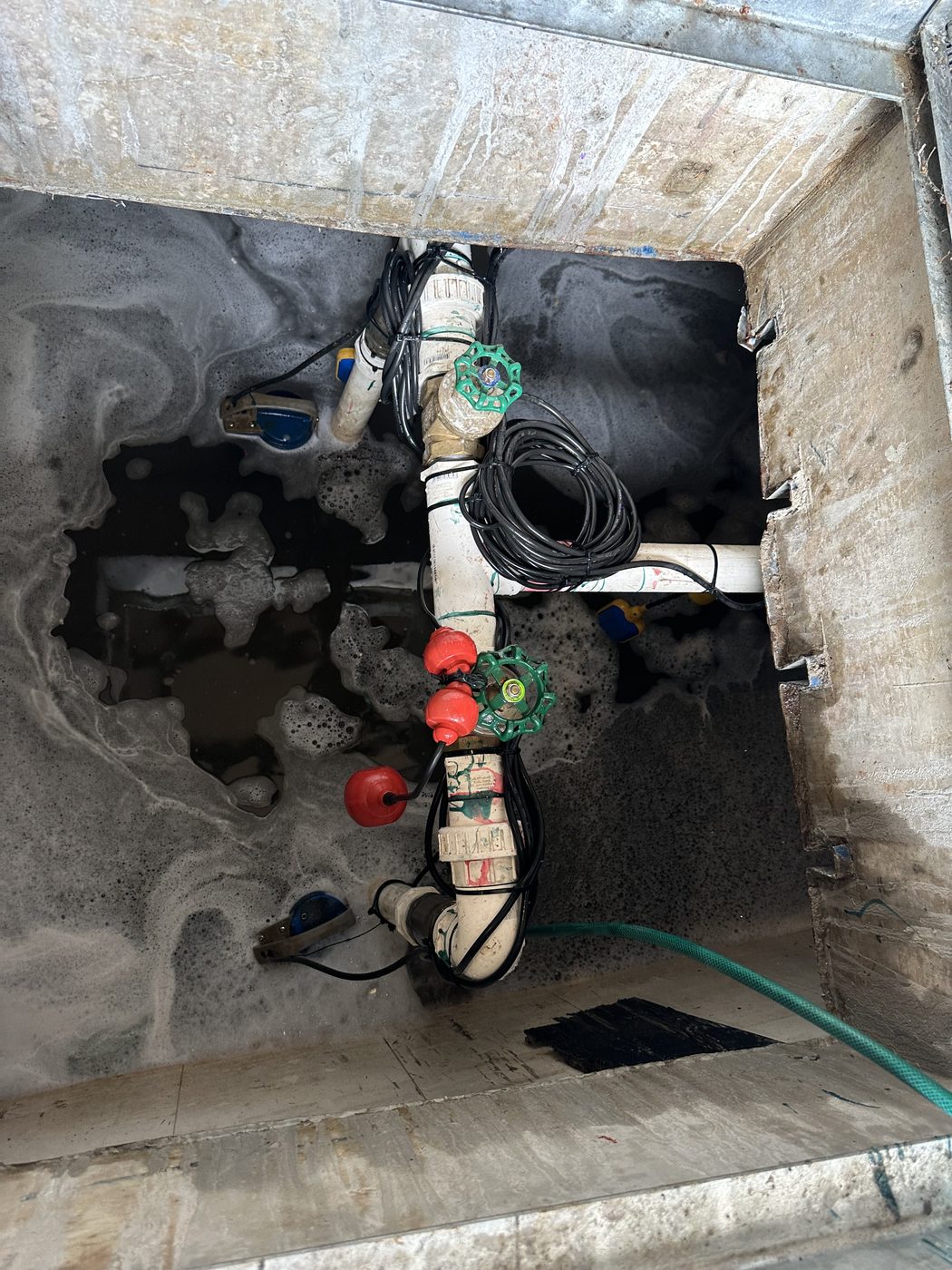 Dual pump configuration in a concrete-encased Sydney strata stormwater pit — two submersible pumps with float switches, isolation valves, and tidied cable management on PVC discharge pipework