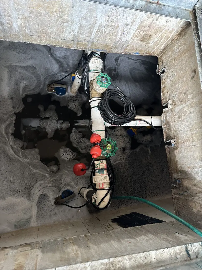 Dual pump configuration in a concrete-encased Sydney strata stormwater pit — two submersible pumps with float switches, isolation valves, and tidied cable management on PVC discharge pipework